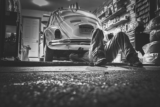 Picture of a man lying under an old Beetle carrying out repairs