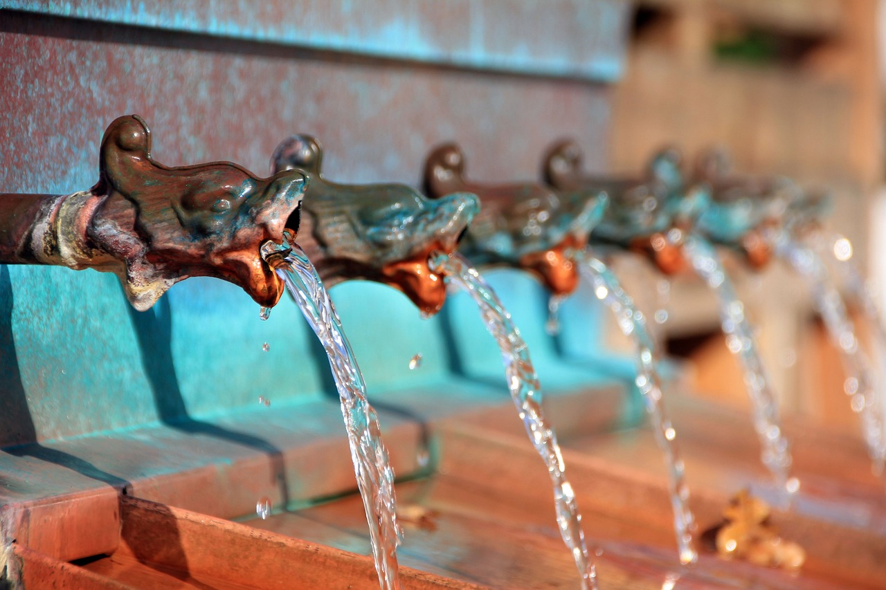 Ein Bild von alten mittelalterlichen Rohren in einem Brunnen, aus dem Wasser austritt, als Metapher für Datenströme.